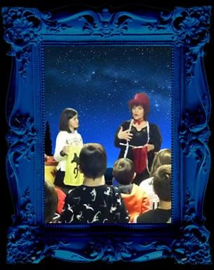 Magic valery speaks to an audience of children, in the background a starry night